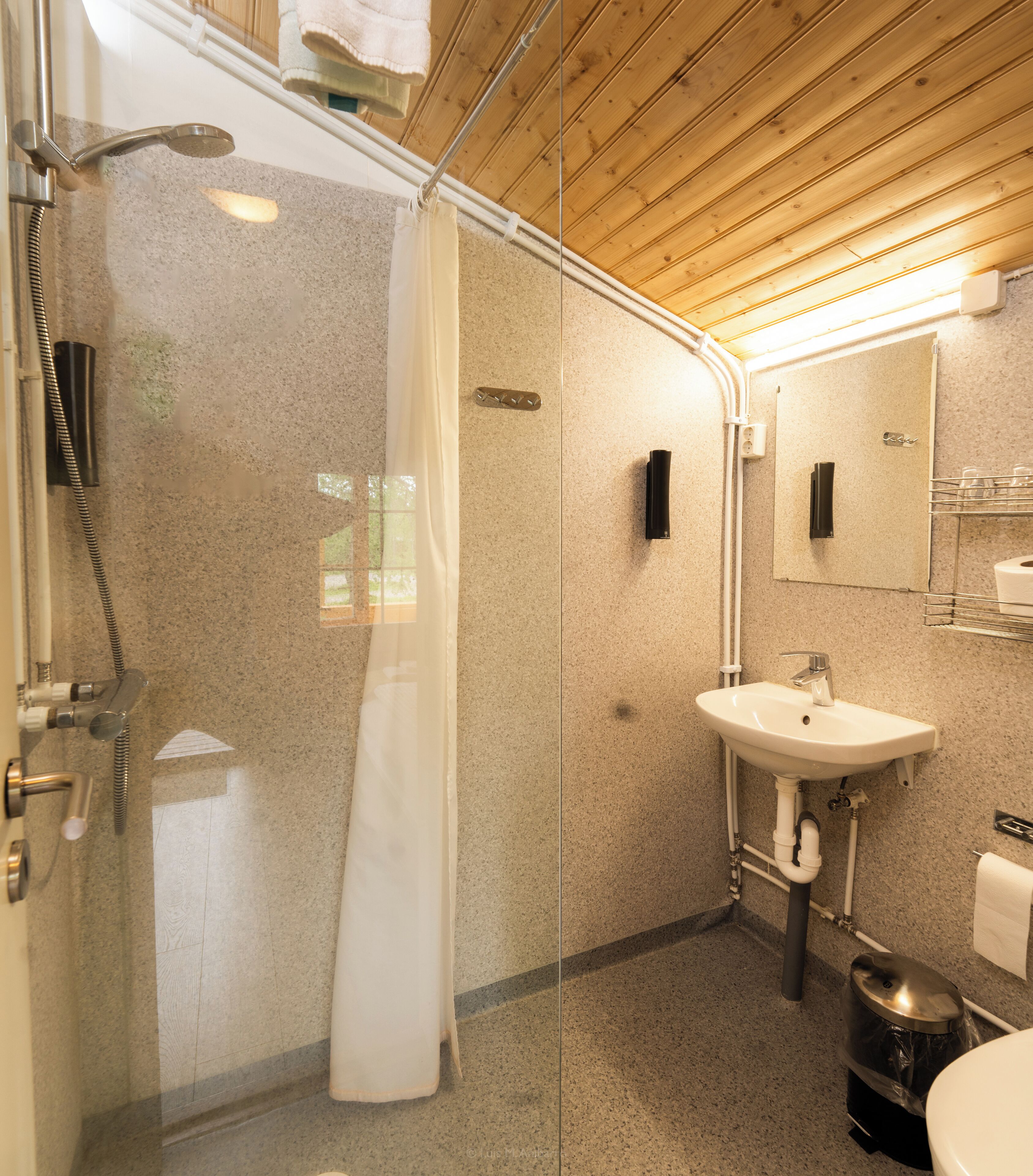 Un baño moderno con ducha de vidrio, lavamanos e inodoro.