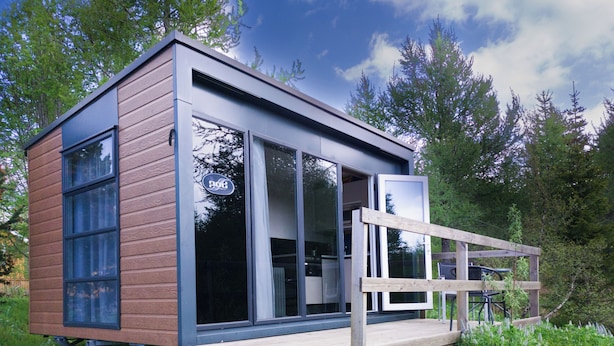 A modern cabin with large windows, a wooden deck, and a surrounding forest. - Hotel Eyvindará (Egilsstaðir)