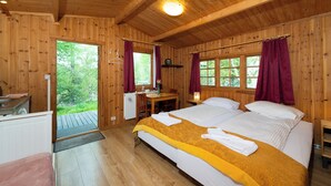 A wooden cabin with a double bed, a desk, and a view of the outdoors. - Hotel Eyvindará (Egilsstaðir)