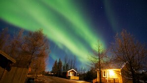 A house with a wooden deck and a small porch, surrounded by leafless trees. - Hotel Eyvindará (Egilsstaðir)