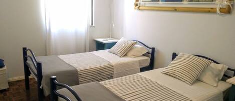 A room with two single beds, a nightstand, a lamp, and a painting on the wall.