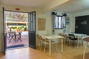 Una stanza con zona pranzo, lavagna con scritte e cartello che indica l'uscita.