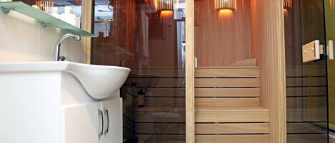A modern bathroom with a glass-enclosed shower, wooden flooring, and a white sink.