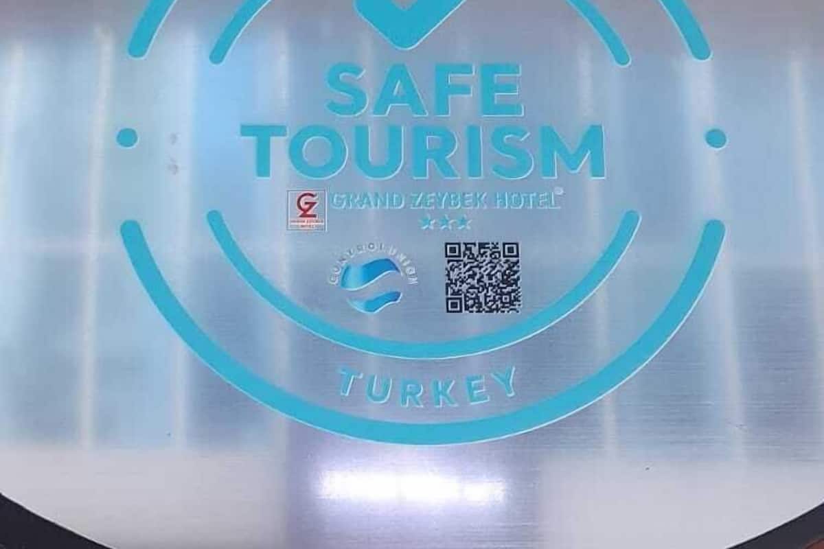 Une plaque métallique portant l’inscription « CERTIFICAT DE TOURISME SÉCURISÉ » et « GRAND ZAYBEK HOTEL TURQUIE », fixée sur une surface en bois.