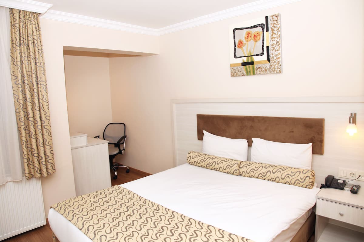 Une chambre d’hôtel équipée d’un lit, d’un bureau, d’une chaise et d’un téléphone.