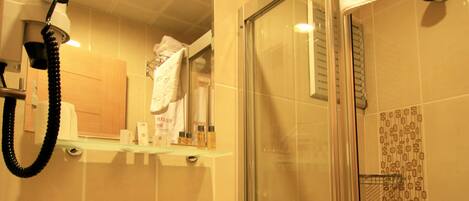 A bathroom with a sink, mirror, and shower. A towel hangs on the wall, and a sign reads "Grand Zeybek Hotel".