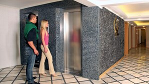 A hallway with a marble wall, a door, and a tiled floor. - Grand Zeybek Hotel (Izmir)