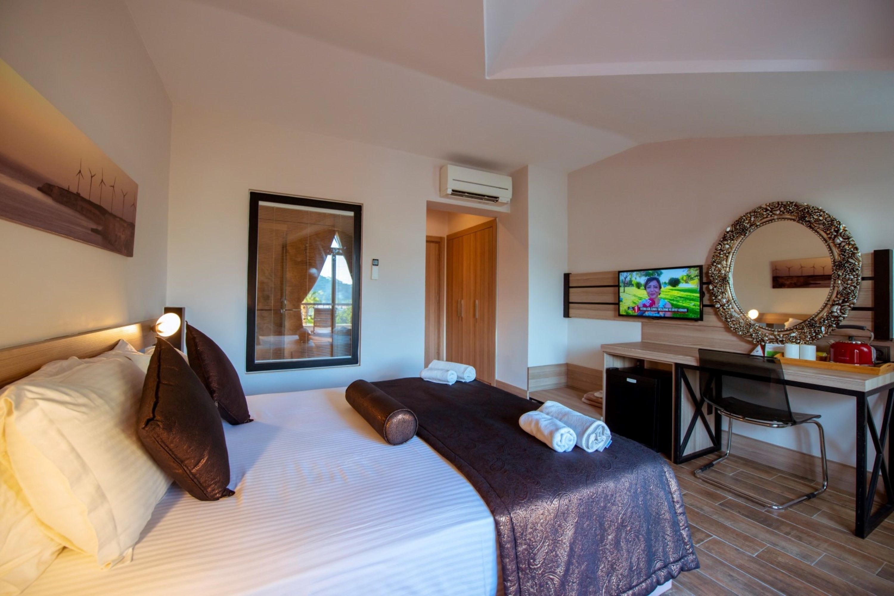 A hotel room with a bed, a desk, a television, and a mirror.