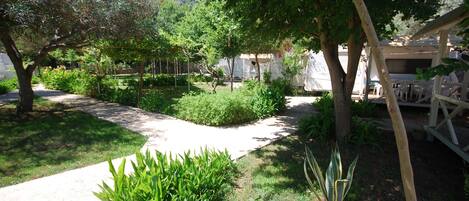 Un sendero de jardín que conduce a un área de estar techada con mesas y sillas.