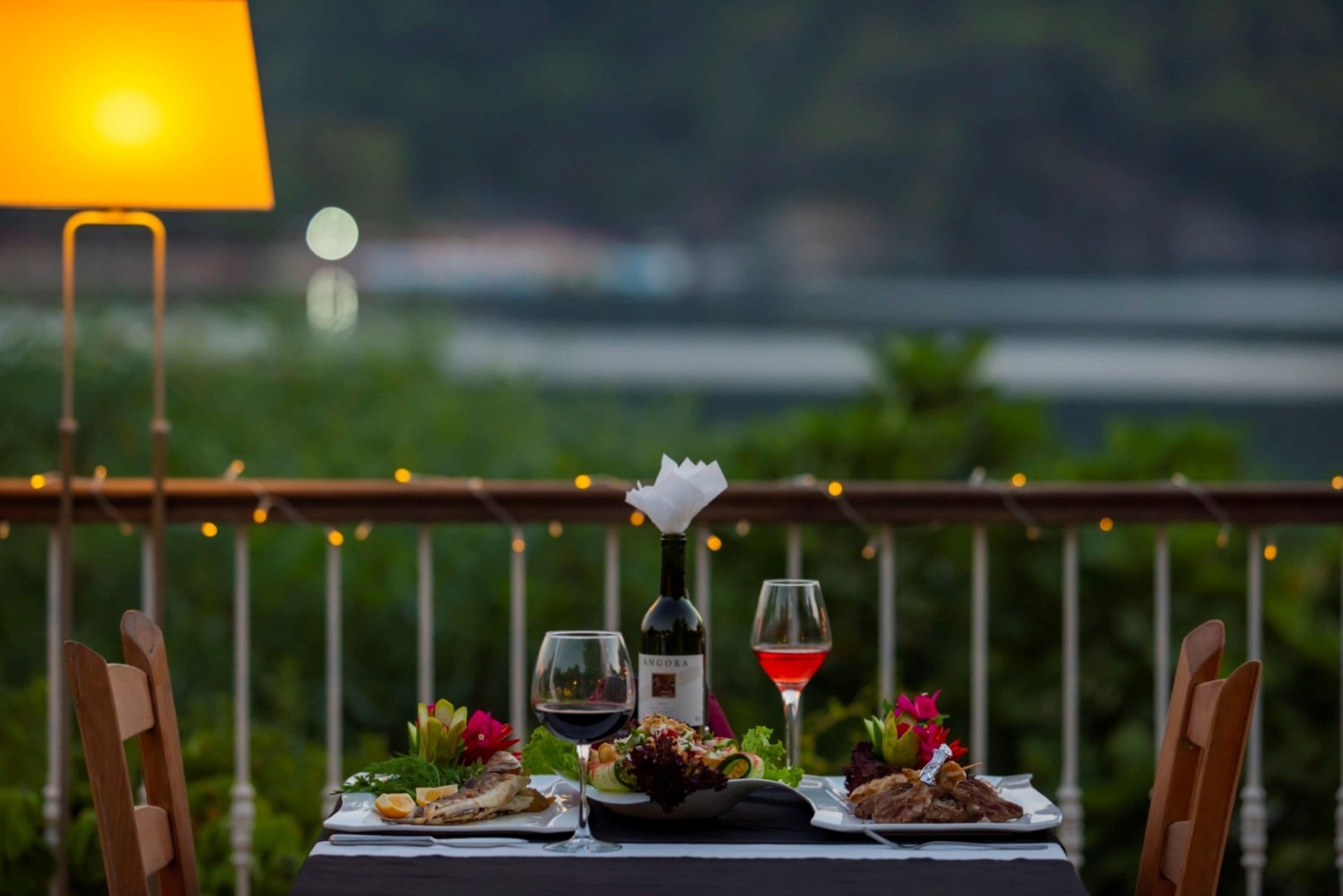 Une table dressée pour un repas, avec une bouteille de vin, des verres et des assiettes remplies de nourriture.