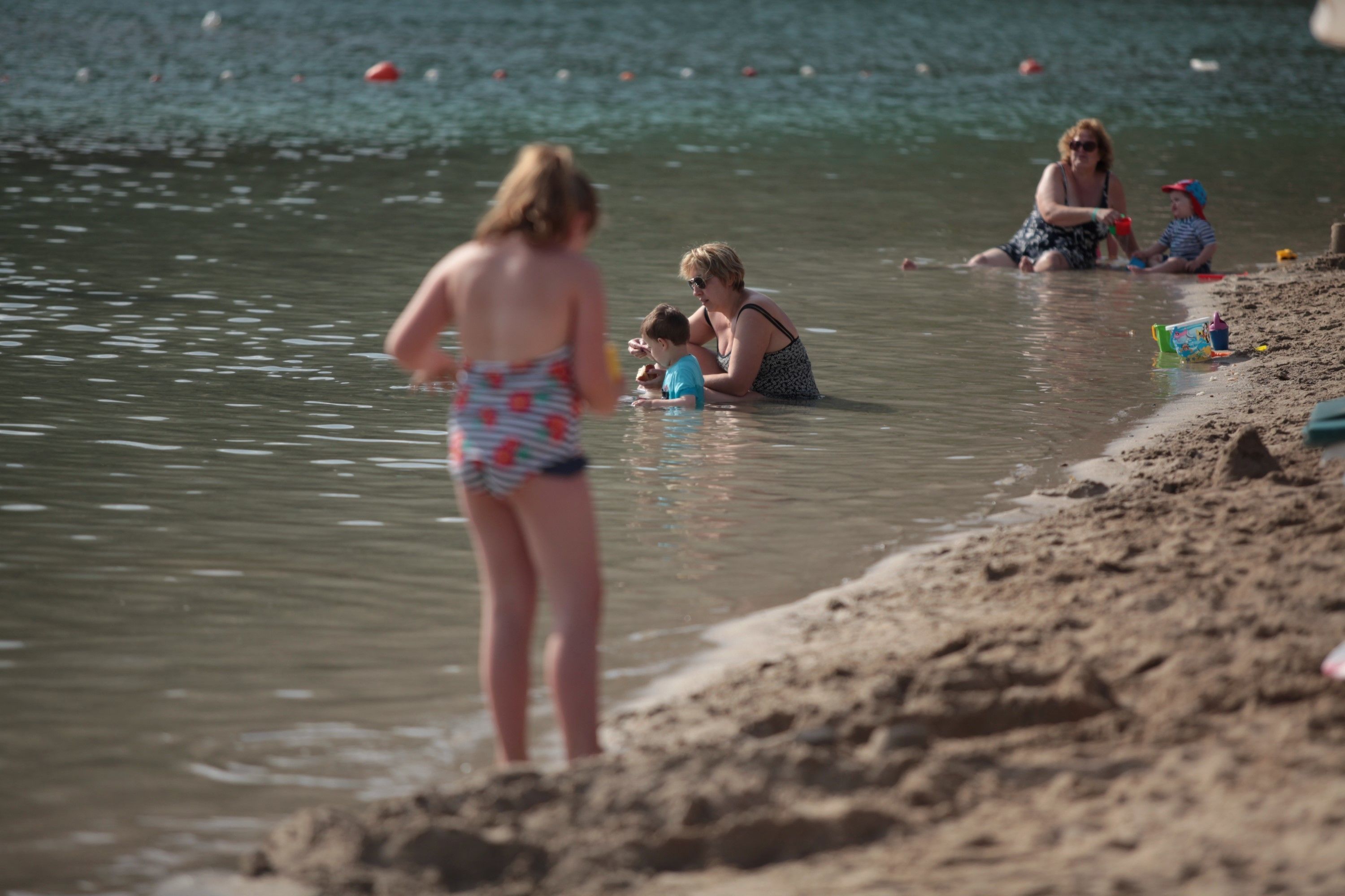 Escena de playa con gente en el agua y sobre la arena.