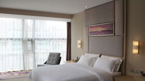 A hotel room with a large bed, a chair, a nightstand, and a painting on the wall. - Lavande Hotel GZ LongDong Metro Station Branch (Guangzhou)