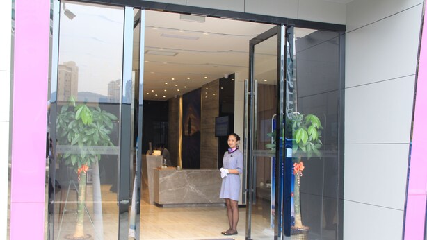 A hotel reception area with a receptionist, a reception desk, and potted plants. - Lavande Hotel GZ LongDong Metro Station Branch (Guangzhou)