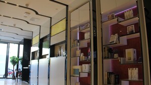 A modern interior with a reception desk, glass display shelves, and a potted plant. - Lavande Hotel GZ LongDong Metro Station Branch (Guangzhou)
