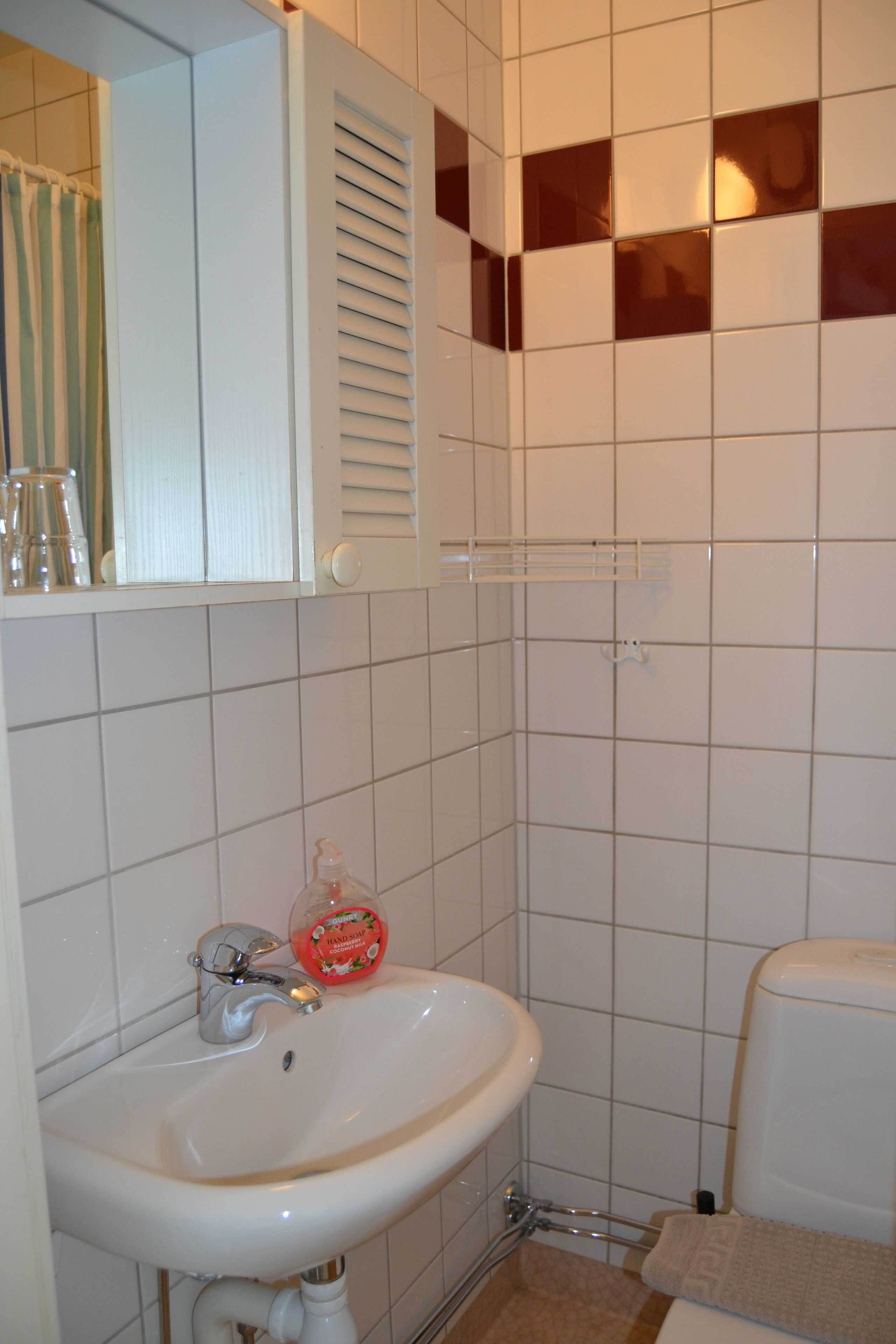 A bathroom with a white sink, a mirror, and a toilet.