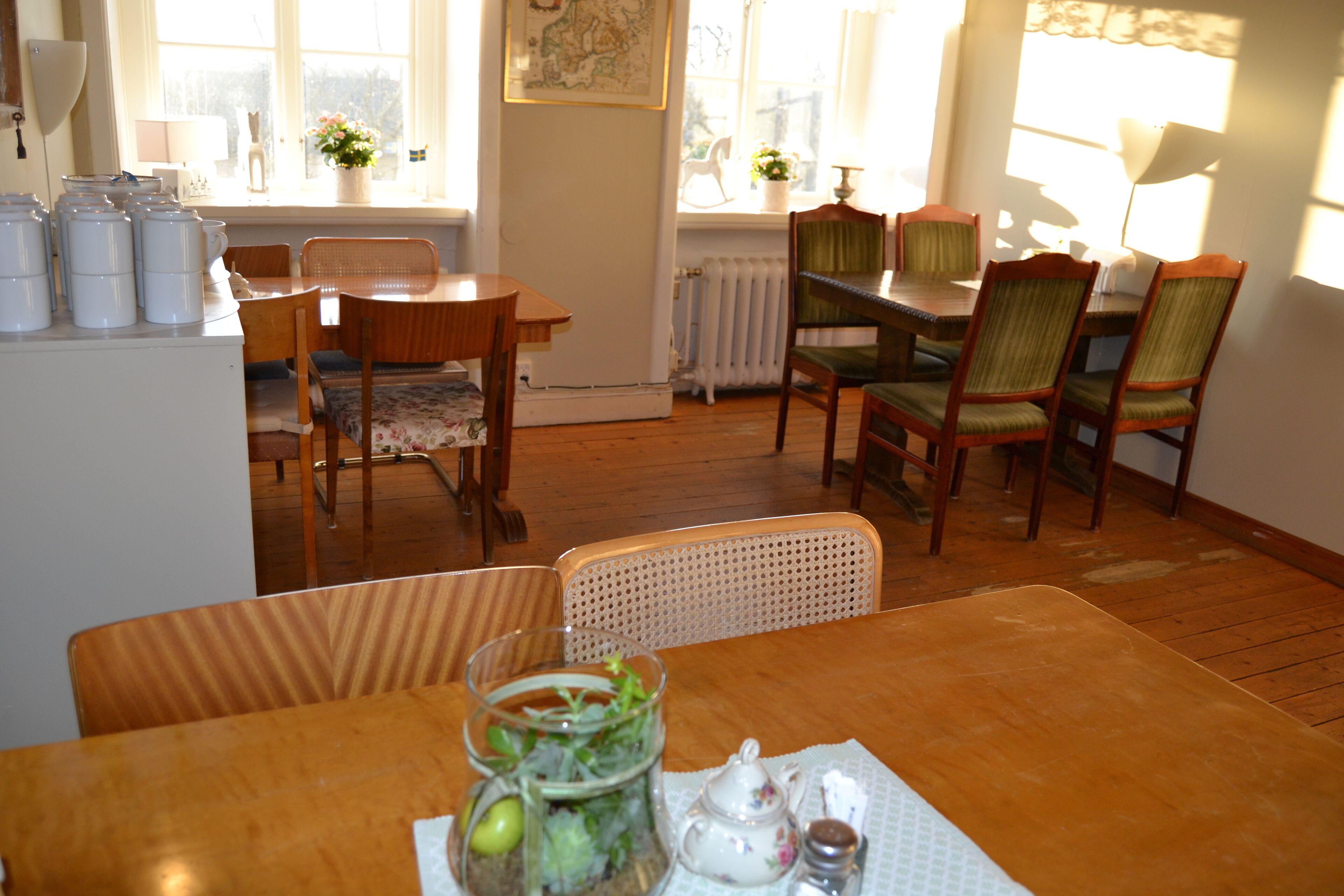 A dining area with wooden furniture, a table with a glass jar of salad, and a radiator in the background.