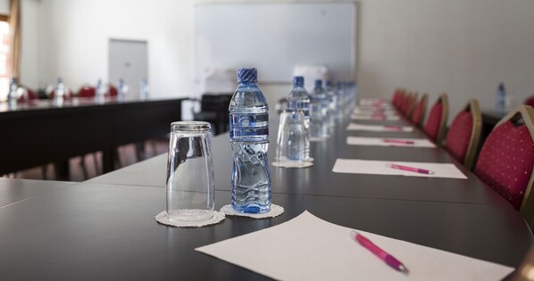 Una mesa de conferencias con botellas de agua, papeles y bolígrafos.