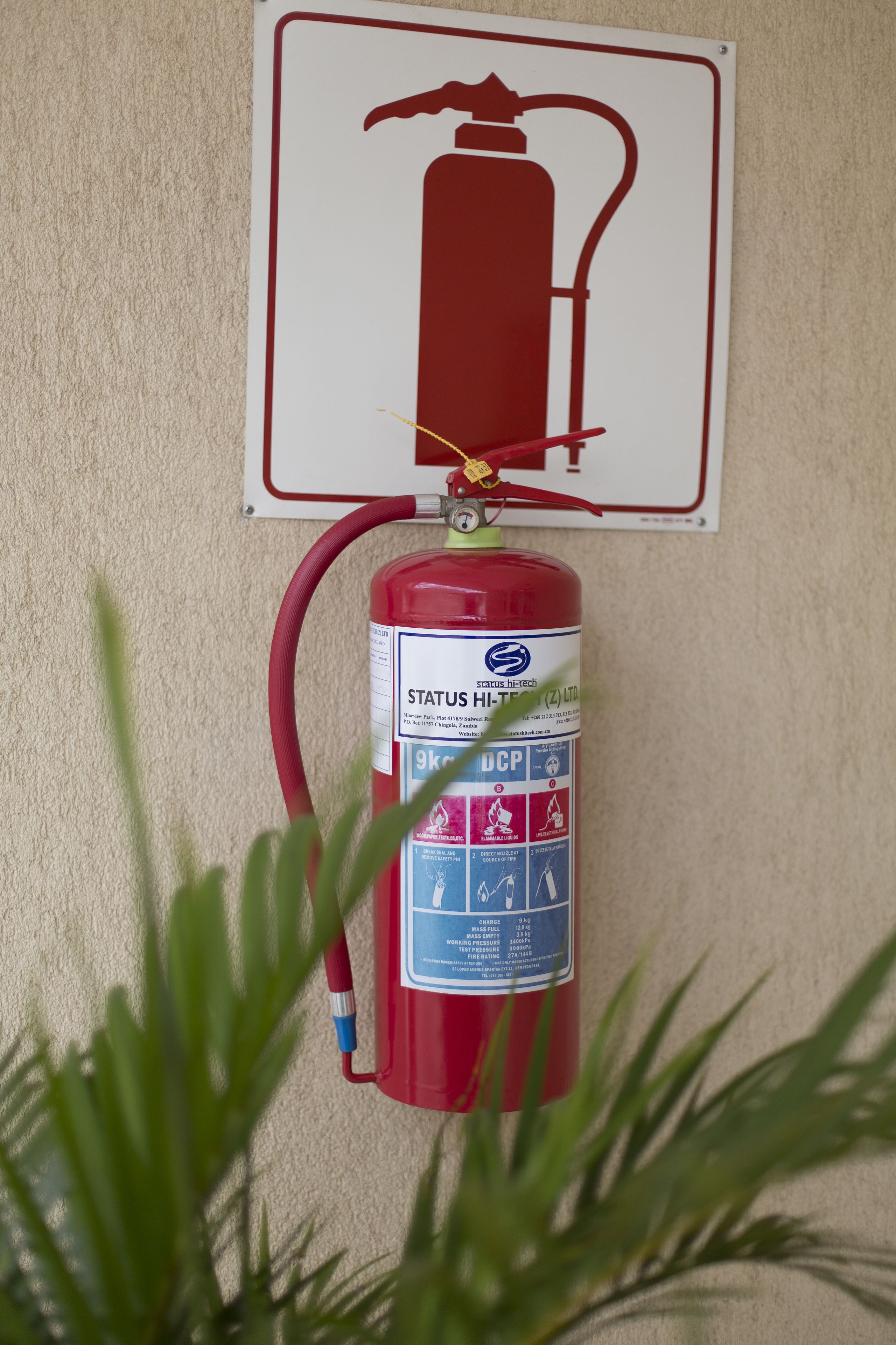 Un extintor fijado a la pared con un cartel de seguridad contra incendios encima.