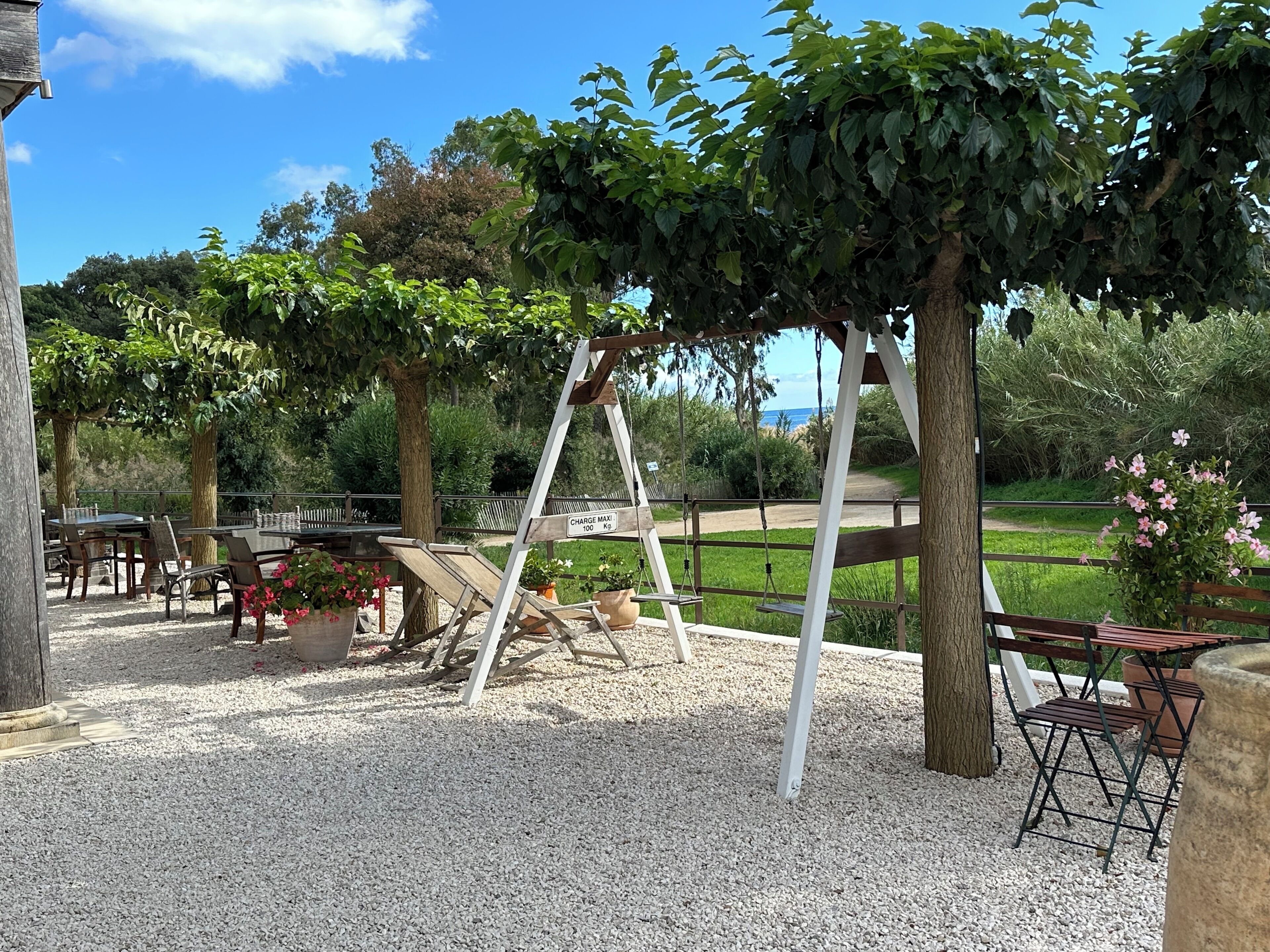 A patio area with a table and chairs, a swing set, and a view of the sea.