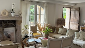 A cozy living room with a fireplace, comfortable seating, and large windows allowing natural light. - Le clos des sept palmiers (Cavalaire-sur-Mer)