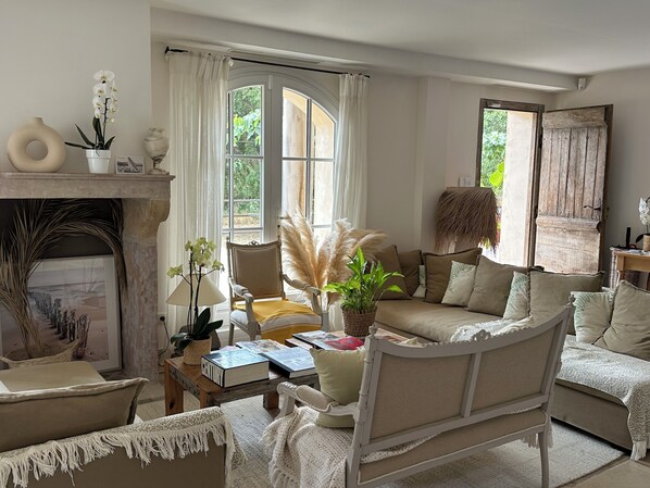 A cozy living room with a fireplace, comfortable seating, and large windows allowing natural light. - Le clos des sept palmiers (Cavalaire-sur-Mer)
