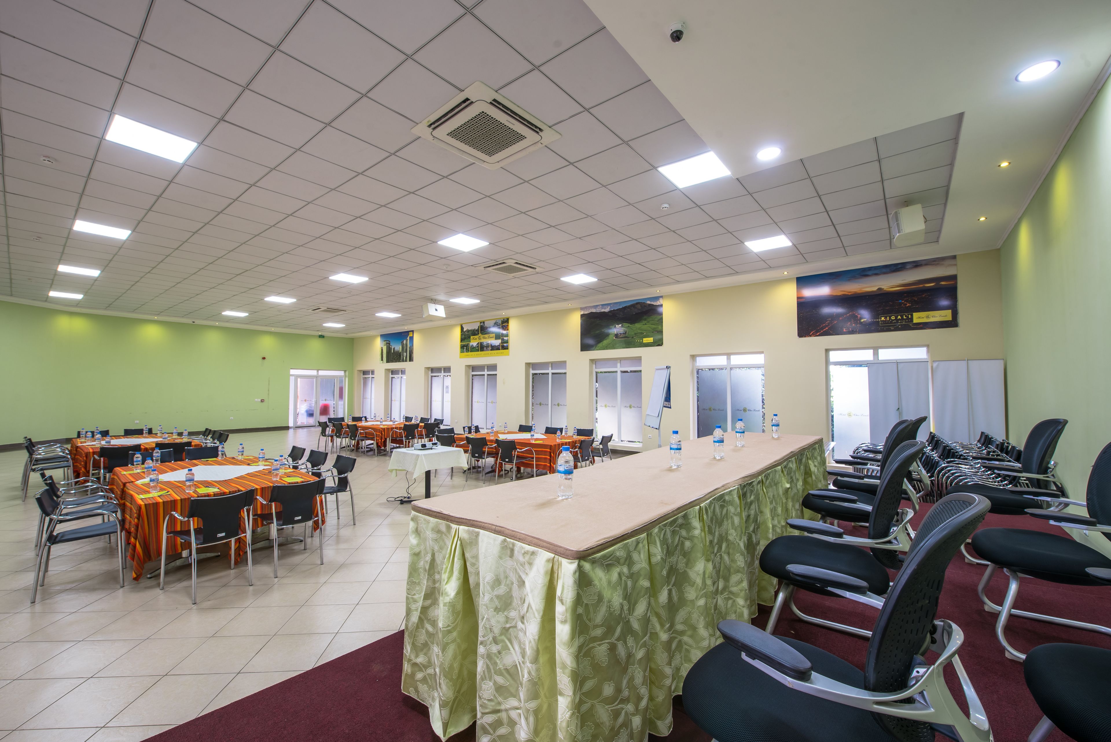 A conference room with multiple tables and chairs, equipped with water bottles and a projector.