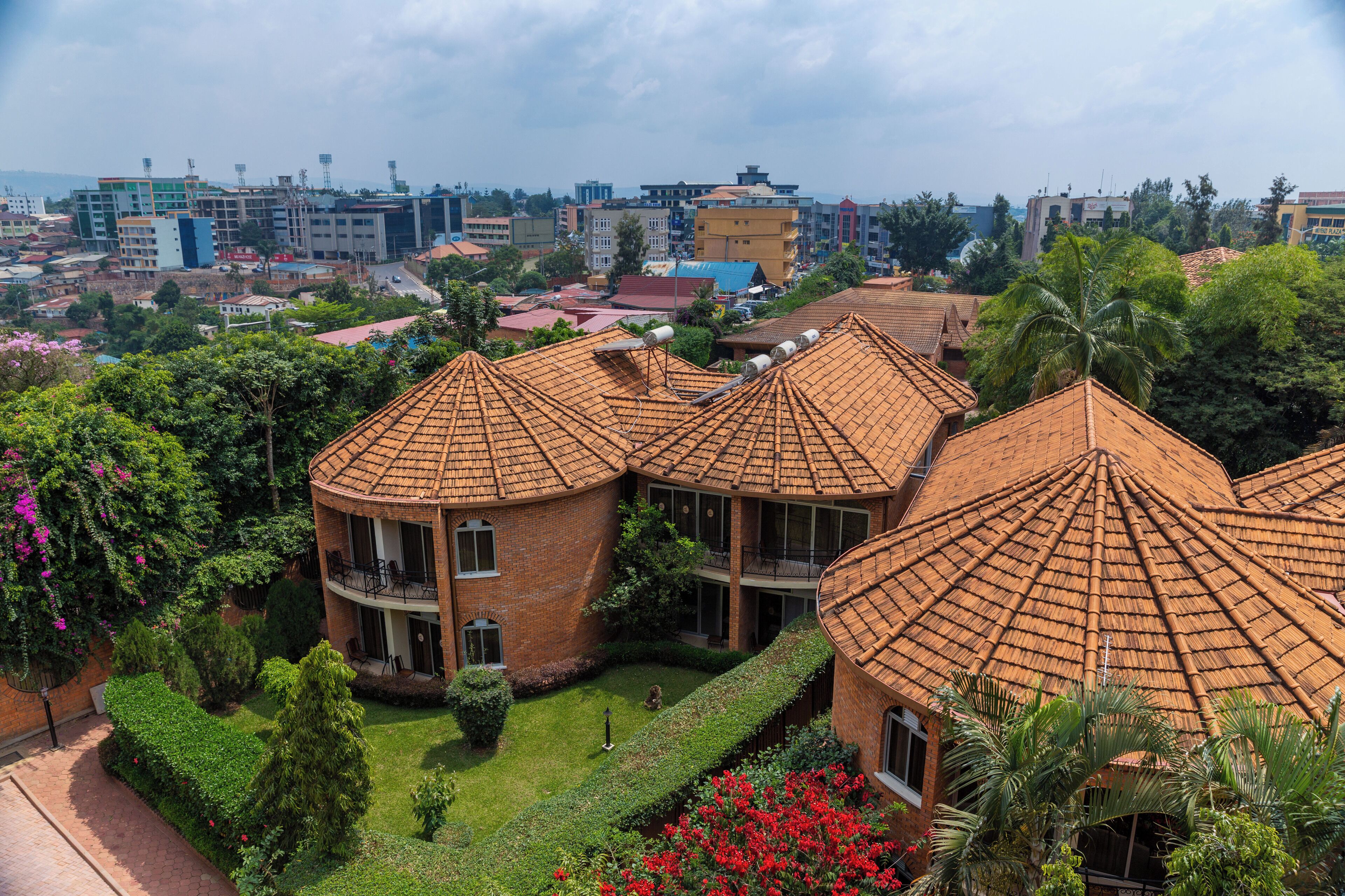 A multi-story building with a curved roof, surrounded by lush greenery and a well-maintained garden.