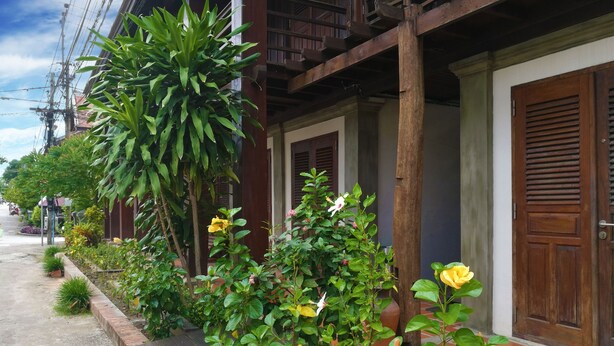 A traditional wooden house with a tiled porch, a wooden door, and a balcony with railings. - Ancient Luang Prabang Hotel (Luang Prabang)