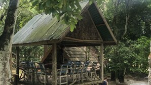 A wooden structure with a metal roof, surrounded by lush greenery, overlooking a fast-flowing river. - Ancient Luang Prabang Hotel (Luang Prabang)