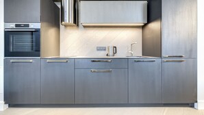 A modern kitchen with grey cabinetry, a built-in oven, and a stainless steel faucet. - Vilnius Apartments & Suites - Town Hall (Vilnius)