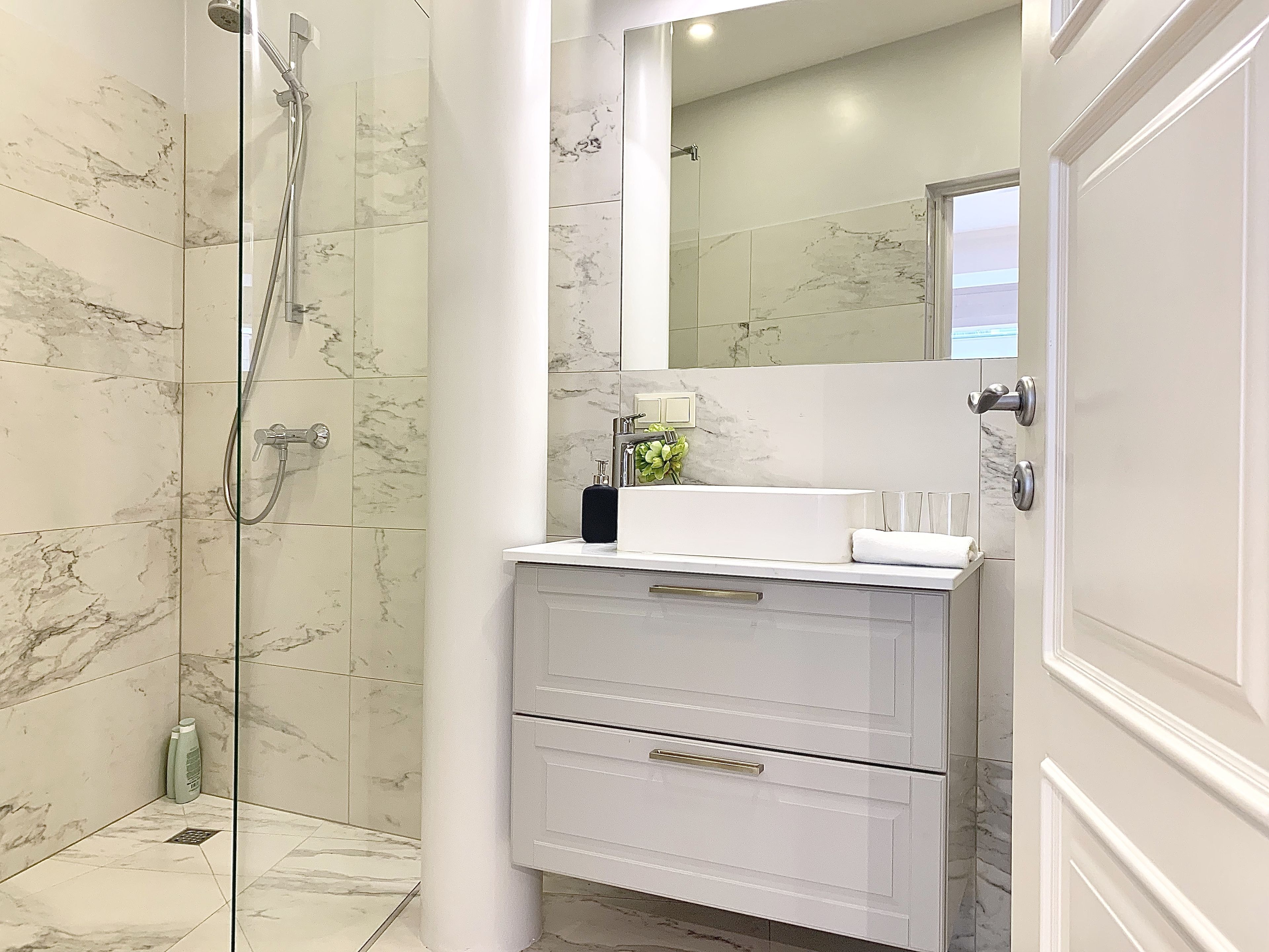 A bathroom with a shower, a sink, and a mirror.