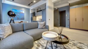 A modern living room with a grey sectional sofa, a round coffee table, and a painting on the wall. - Vilnius Apartments & Suites - Town Hall (Vilnius)
