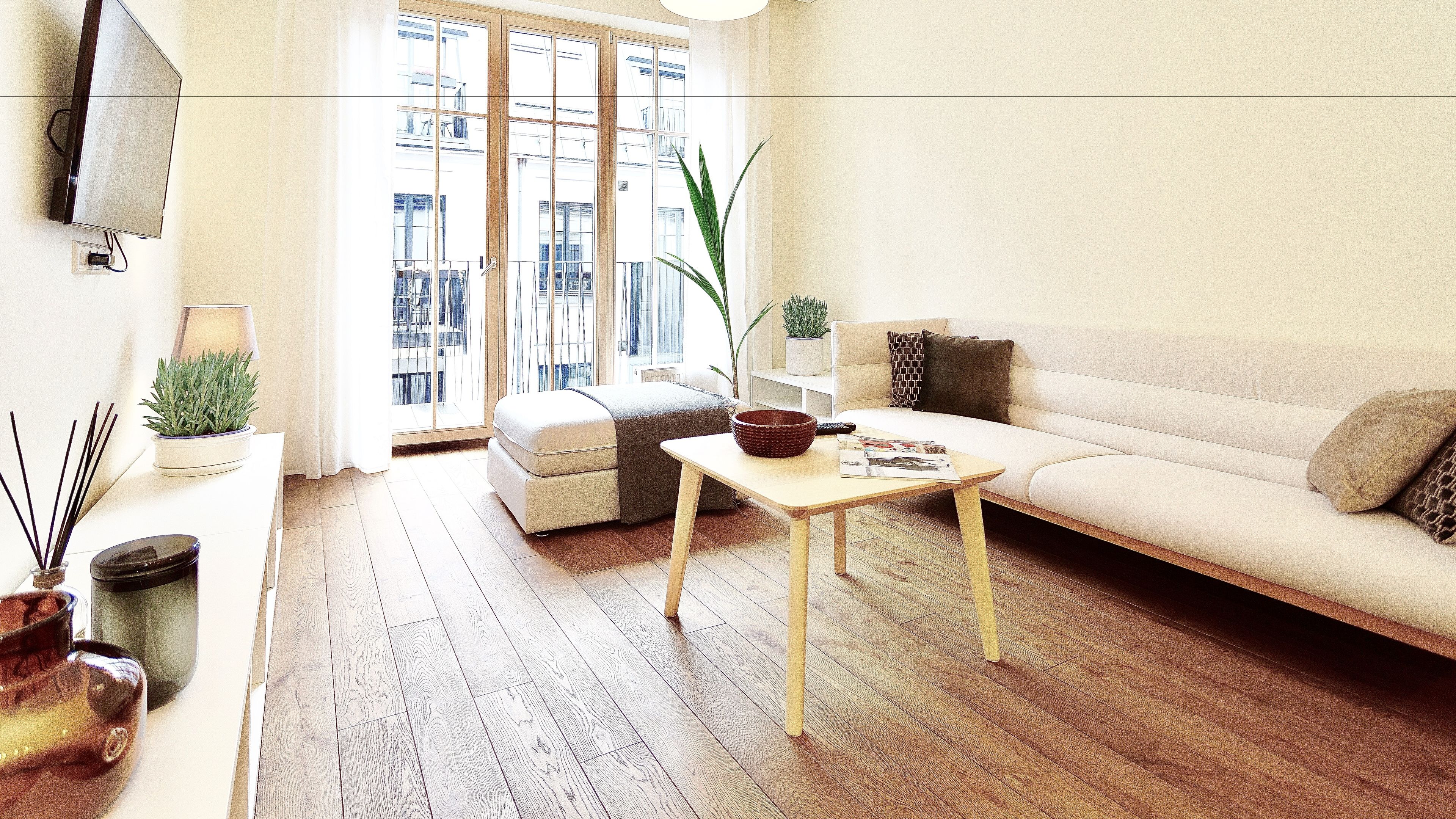 A living room with a sofa, a coffee table, a small table with a bowl, a lamp, and a potted plant.