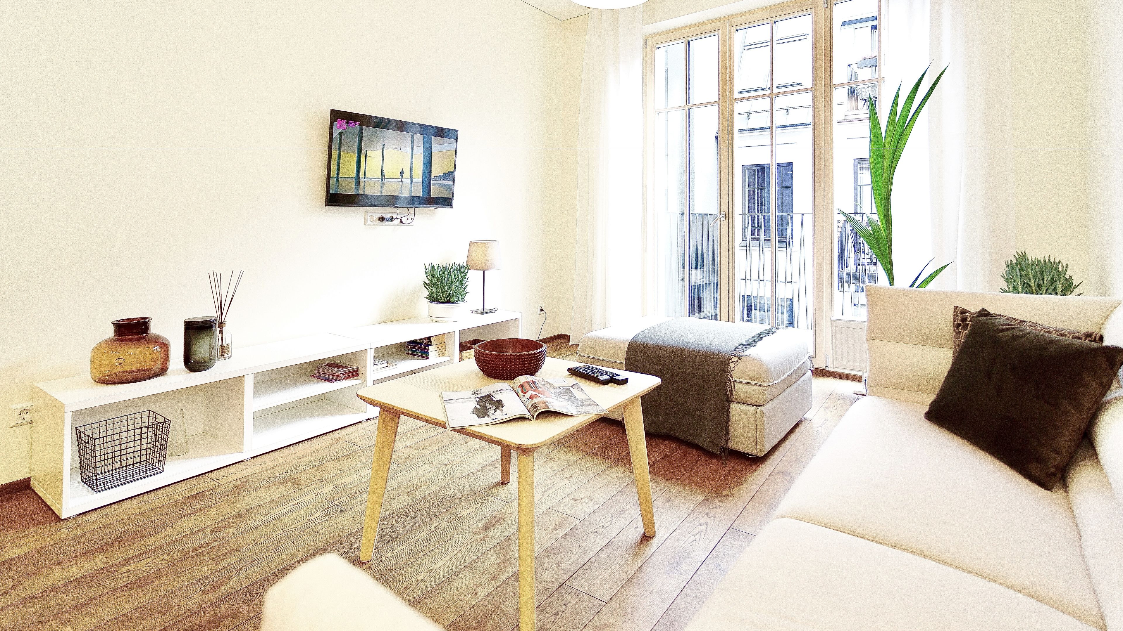 A modern living room with a sofa, a coffee table, and a TV mounted on the wall.