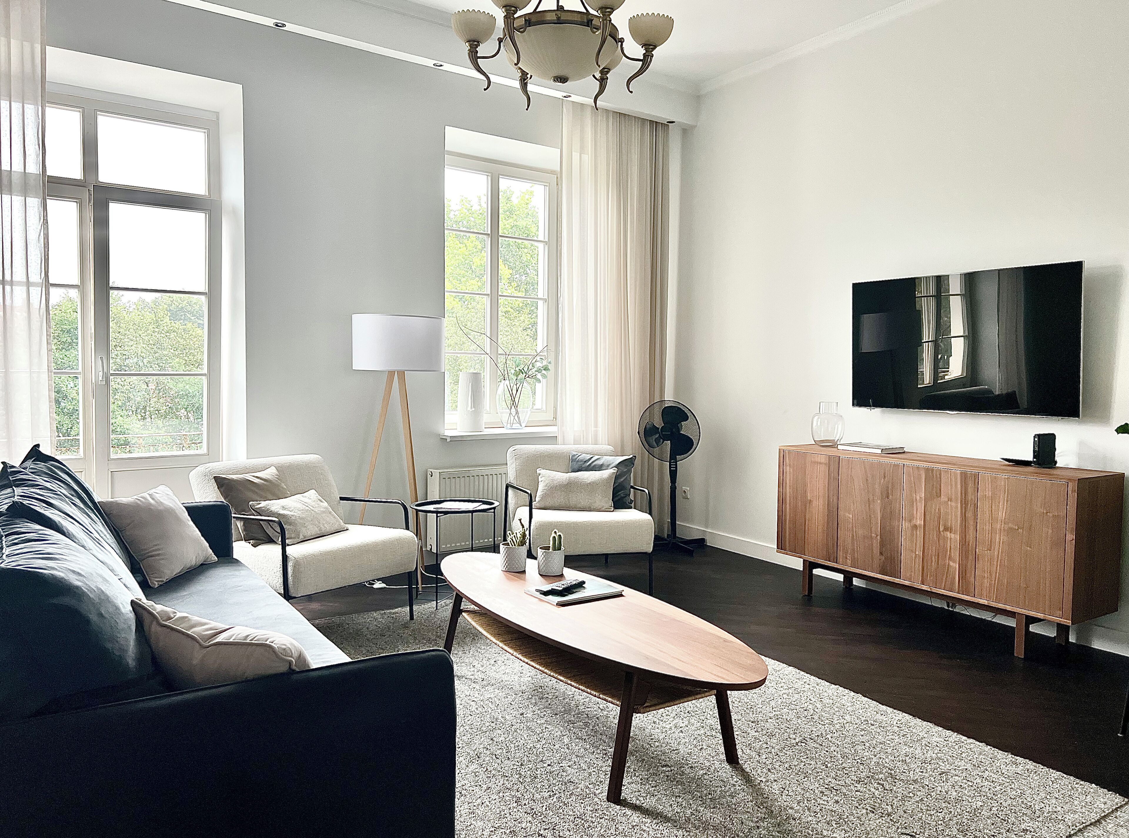 Un salon moderne comprenant un canapé, des fauteuils, une table basse, un téléviseur et un meuble en bois.