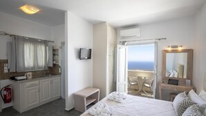 Una camera d'albergo con un letto, una scrivania, una sedia, una televisione e vista sull'oceano.