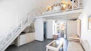 Un'ampia cucina con isola centrale, un'area pranzo con una panca e una scala che conduce a un piano superiore.