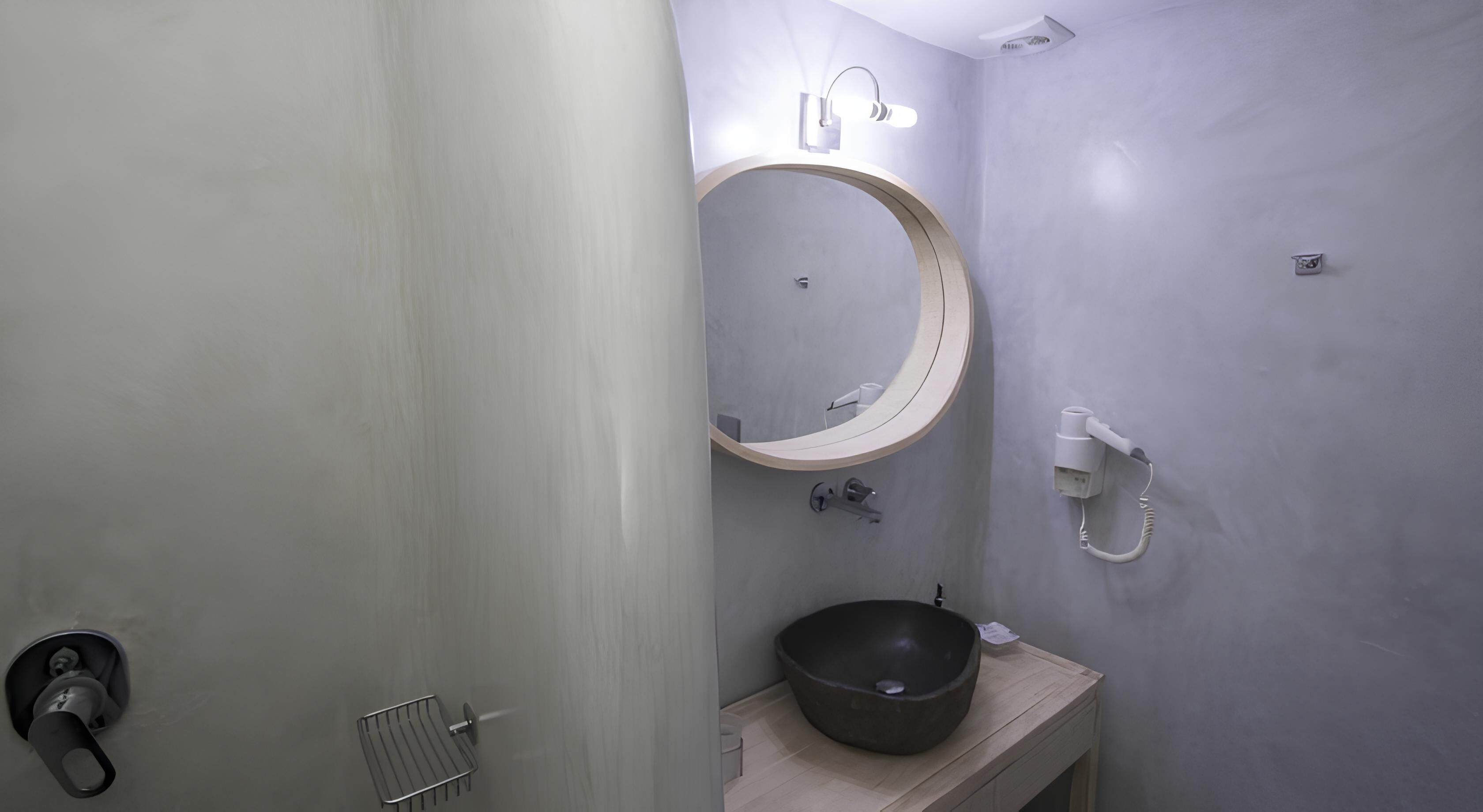 A bathroom with a round mirror, a sink, and a shower.