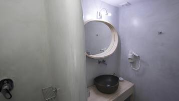 A bathroom with a round mirror, a sink, and a shower.