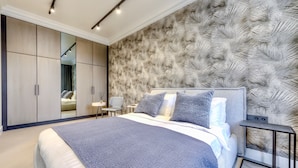 Un dormitorio moderno con una cama grande, un armario, un espejo y una pared con diseño de hojas.