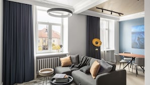 Una sala de estar moderna con un sofá gris, una mesa de centro redonda y un comedor con una mesa y sillas de madera.