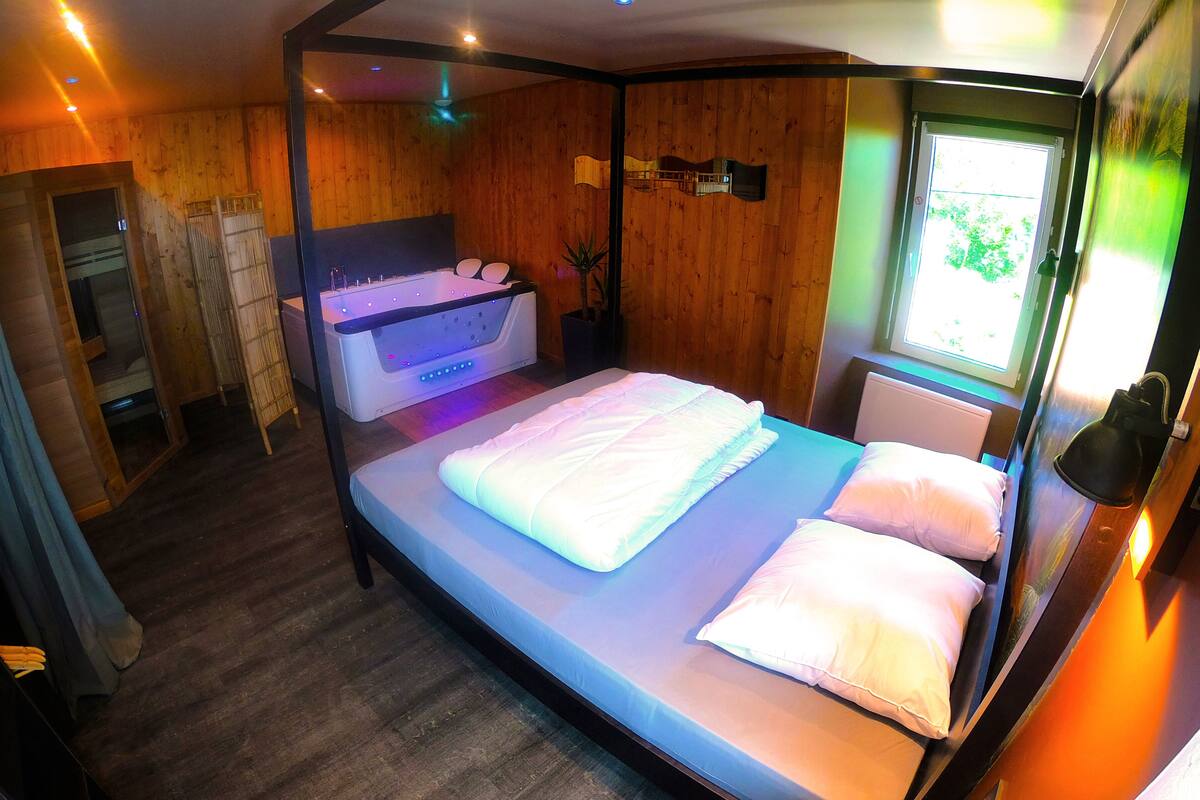 Quarto com cama, janela e uma pequena mesa com uma planta.