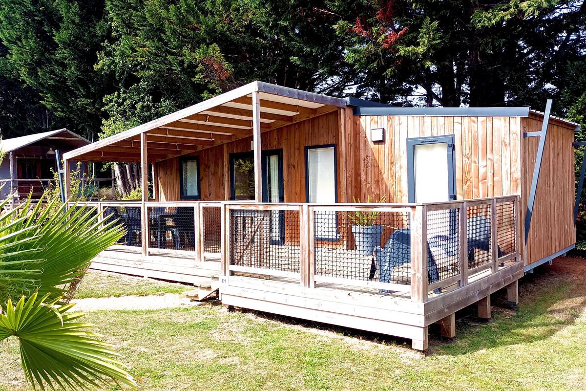 Uma cabana de madeira com varanda coberta e um deck cercado.
