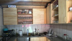 A kitchen with wooden cabinets, a granite countertop, and various kitchen appliances. - Mencuna Konaklari (Arhavi)