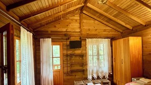 A wooden cabin with a high ceiling, a bed, a desk, and a television. - Mencuna Konaklari (Arhavi)