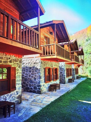 A stone building with wooden balconies and a stone pathway leading to a grassy area. - Mencuna Konaklari (Arhavi)
