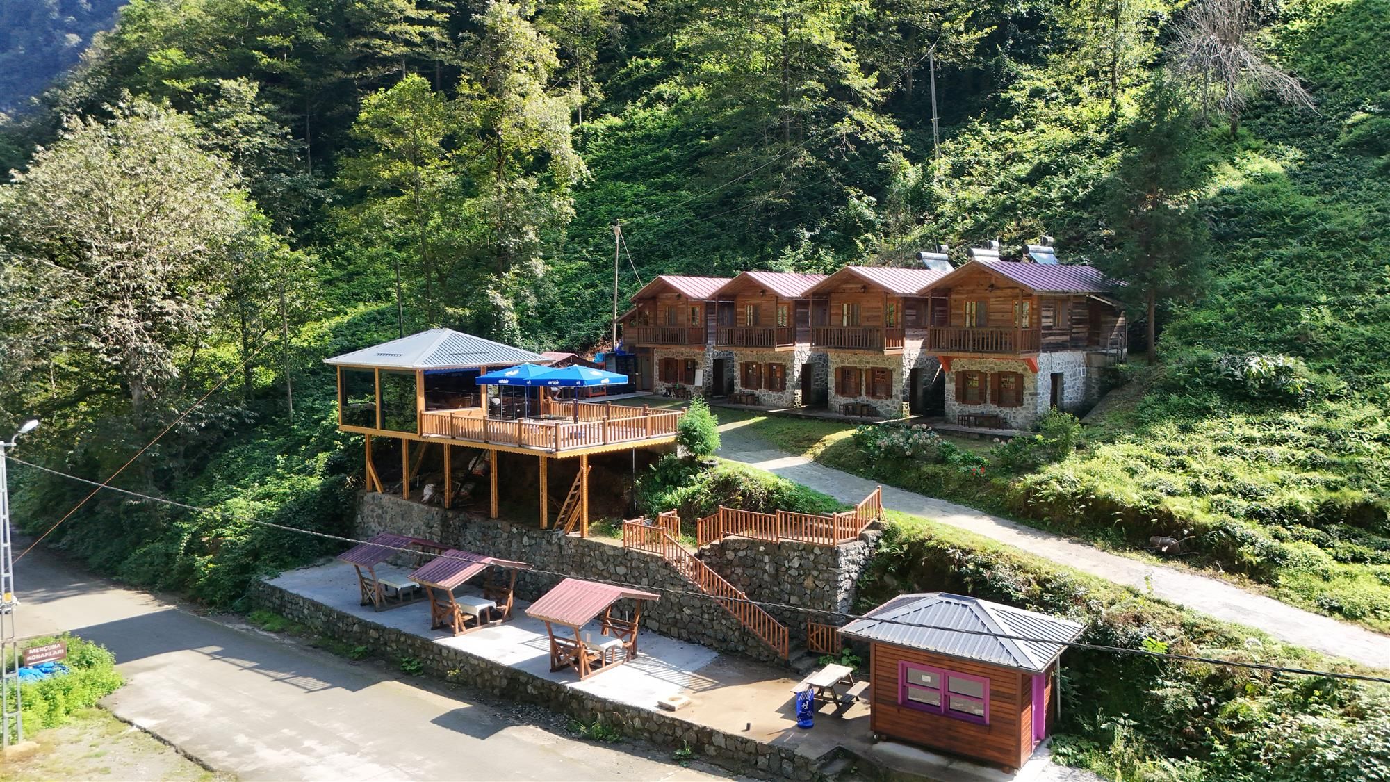 A lodge with multiple wooden cabins, a central building with a balcony, and a small annex.