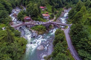 A bridge over a river with a building and cars on the bridge. - Mencuna Konaklari (Arhavi)