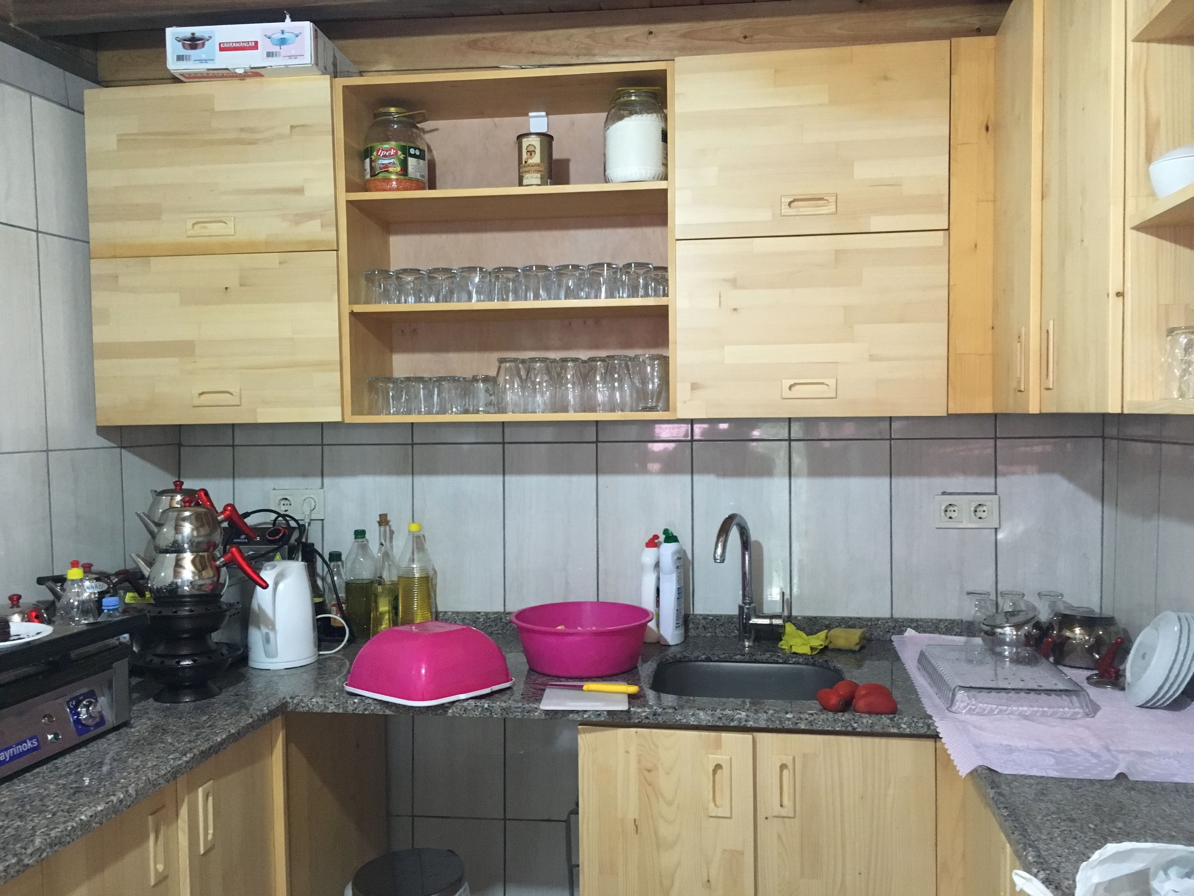 A kitchen with wooden cabinets, a granite countertop, and various kitchen items.