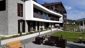 A modern building with a stone facade, a large balcony, and outdoor seating. - Apparthotel Silbersee (Stadl-Predlitz)